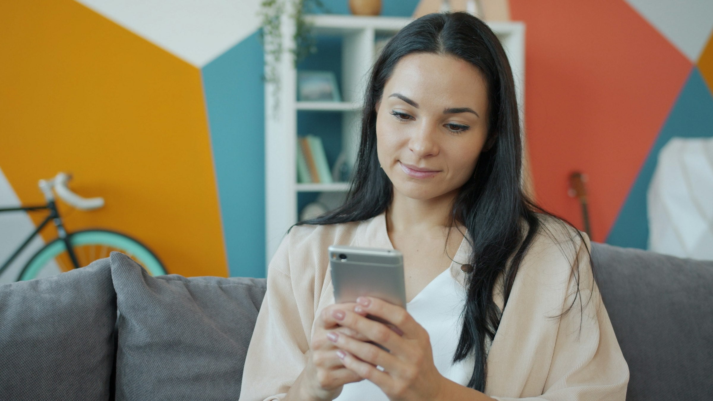 Femme détendue sur son canapé, consultant son téléphone en toute tranquillité